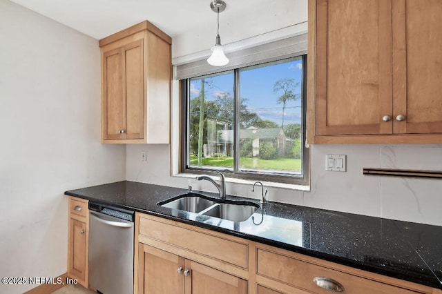 kitchen with hanging light fixtures, stainless steel dishwasher, dark stone countertops, and a sink