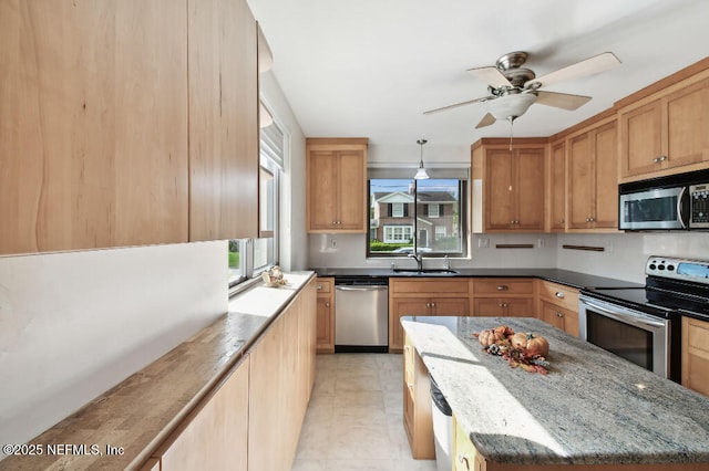 kitchen featuring dark stone counters, appliances with stainless steel finishes, a sink, and a healthy amount of sunlight