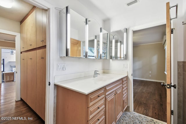 bathroom with baseboards, visible vents, ceiling fan, wood finished floors, and vanity