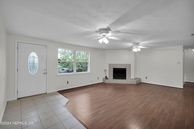 entrance foyer with a textured ceiling, a fireplace, wood-type flooring, and ceiling fan