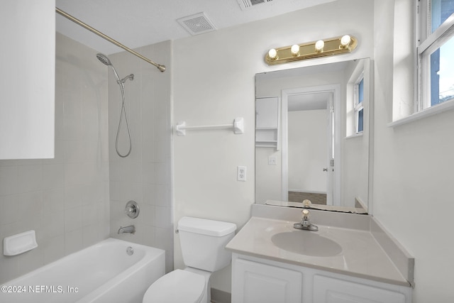 full bathroom featuring a textured ceiling, vanity, tiled shower / bath combo, and toilet