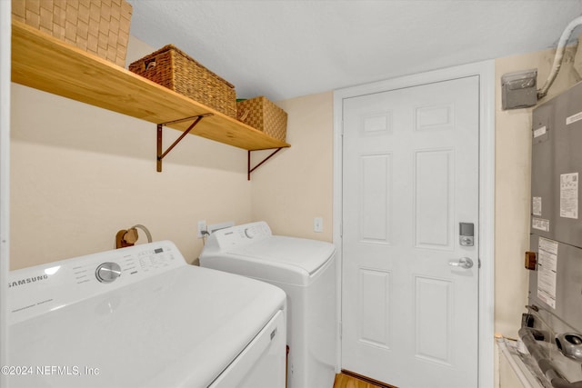 laundry room featuring water heater, a textured ceiling, and washer and dryer