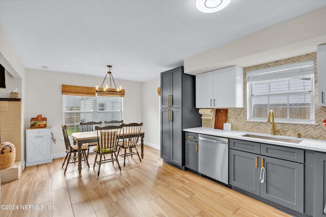 kitchen featuring light hardwood / wood-style floors, sink, stainless steel dishwasher, hanging light fixtures, and gray cabinetry