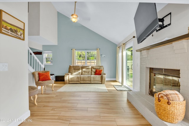 living room with a brick fireplace, high vaulted ceiling, and light wood-type flooring