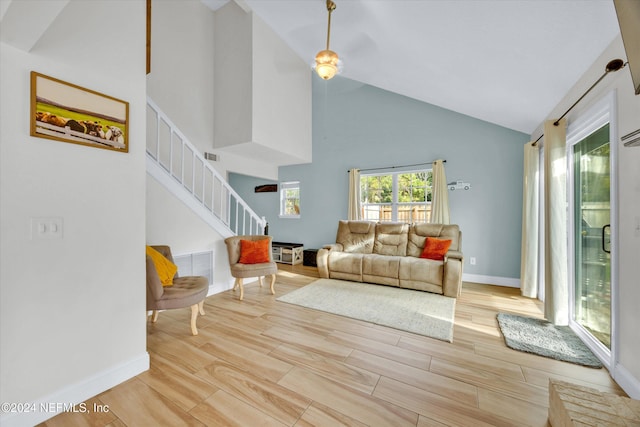 living room with high vaulted ceiling and light hardwood / wood-style floors