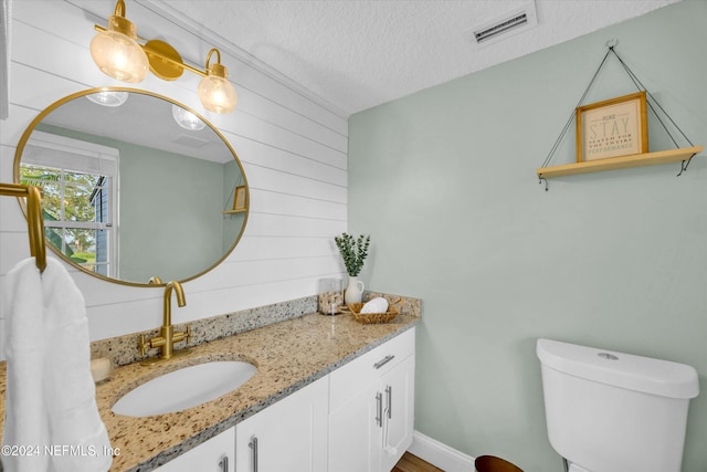 bathroom with vanity, a textured ceiling, and toilet