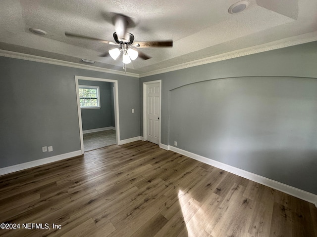 empty room with ceiling fan, wood-type flooring, a textured ceiling, and ornamental molding