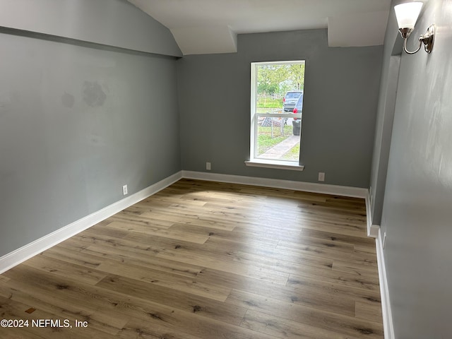 unfurnished room featuring light hardwood / wood-style floors and vaulted ceiling