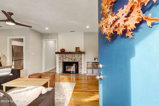 living room featuring ceiling fan, wood-type flooring, and a tile fireplace