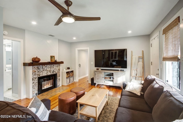 living room featuring a tile fireplace, hardwood / wood-style floors, and ceiling fan