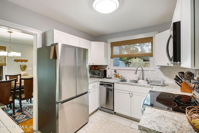 kitchen featuring white cabinetry, sink, hanging light fixtures, stainless steel appliances, and light tile patterned floors