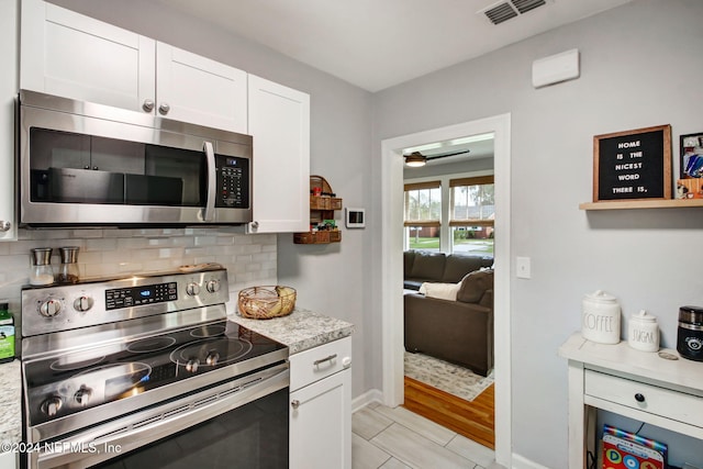 kitchen with white cabinets, decorative backsplash, light stone countertops, and appliances with stainless steel finishes