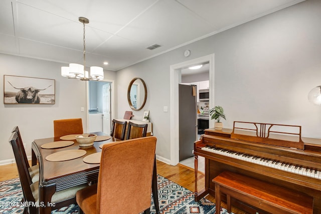 dining area featuring a chandelier, light hardwood / wood-style flooring, and crown molding