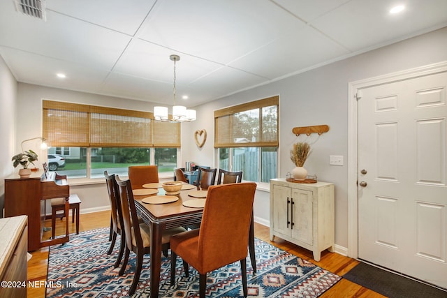 dining space with light hardwood / wood-style flooring and an inviting chandelier