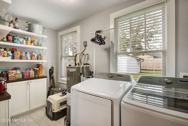 washroom with cabinets, light tile patterned floors, washing machine and dryer, and electric water heater