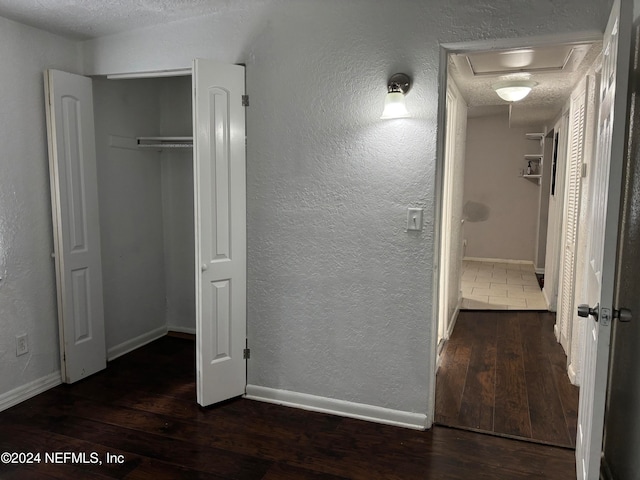 unfurnished bedroom featuring dark hardwood / wood-style flooring, a textured ceiling, and a closet