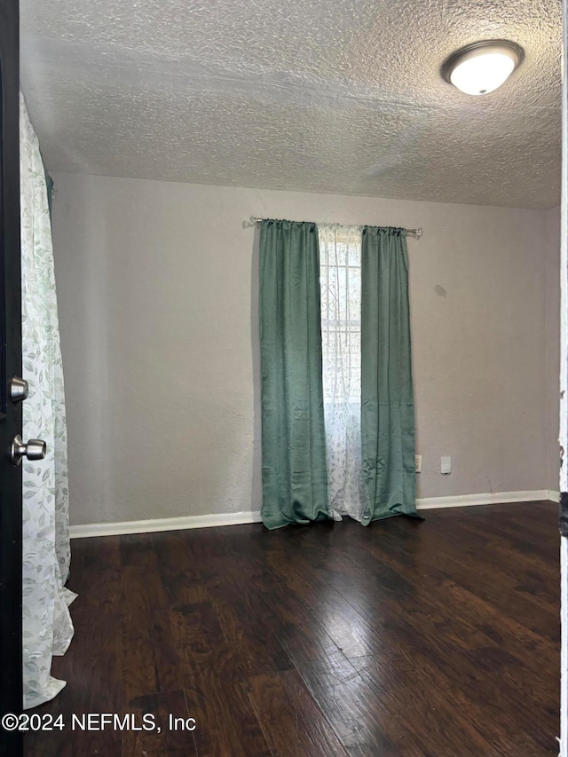 spare room with dark hardwood / wood-style flooring and a textured ceiling