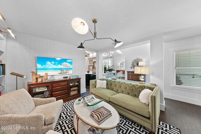 living room with hardwood / wood-style flooring, wooden walls, and an inviting chandelier