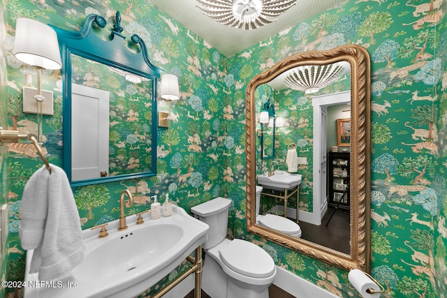 bathroom featuring toilet, sink, and a chandelier