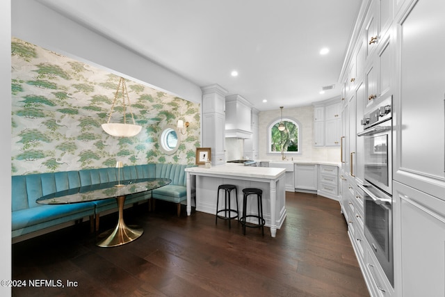 kitchen featuring white cabinets, breakfast area, dark hardwood / wood-style floors, a kitchen island, and a breakfast bar area