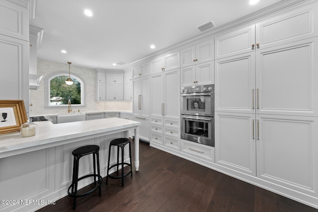 kitchen featuring a breakfast bar, white cabinetry, and stainless steel double oven