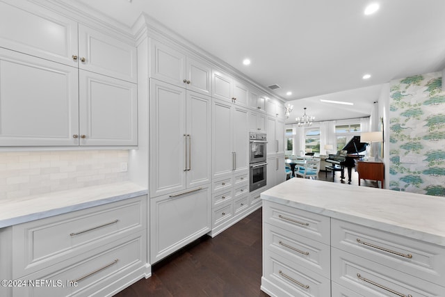 walk in closet with dark wood-type flooring and a notable chandelier