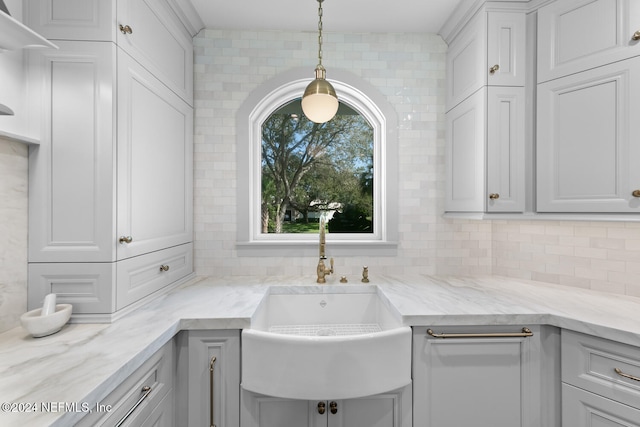 interior space with backsplash, light stone counters, sink, pendant lighting, and white cabinetry