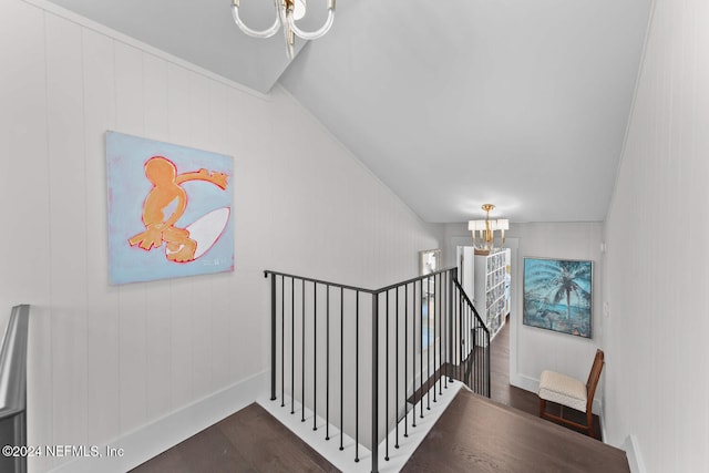 stairway featuring a chandelier, wood-type flooring, and vaulted ceiling