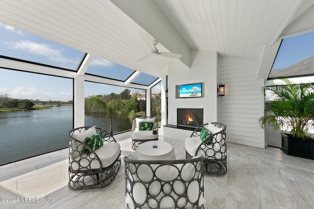 sunroom / solarium with lofted ceiling, a water view, a brick fireplace, and a healthy amount of sunlight