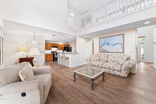 living room featuring hardwood / wood-style floors, a towering ceiling, and a notable chandelier