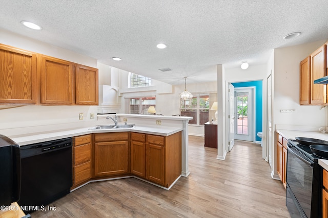 kitchen with light wood-type flooring, pendant lighting, sink, and black appliances