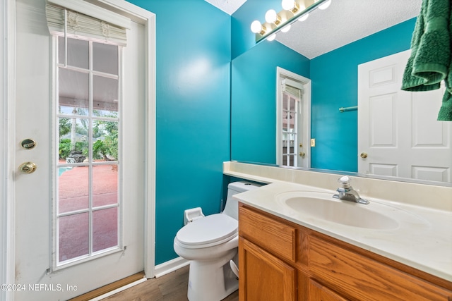 bathroom with vanity, wood-type flooring, a textured ceiling, and toilet