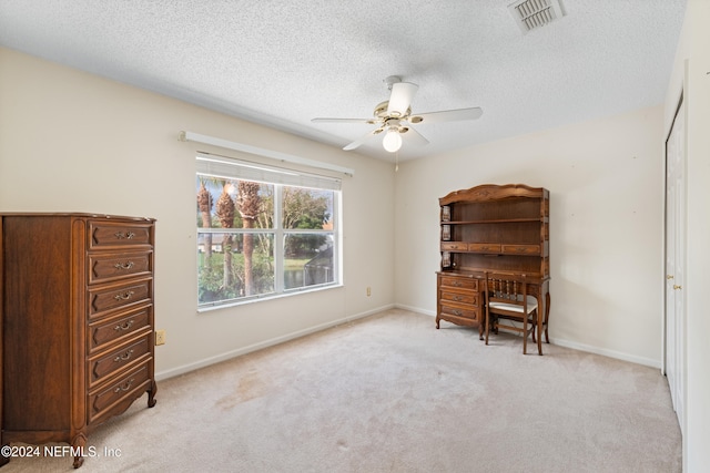 living area with a textured ceiling, light carpet, and ceiling fan