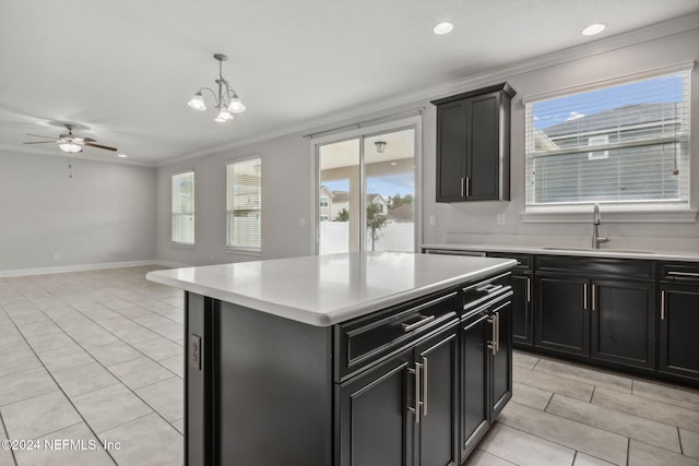 kitchen with a center island, sink, light tile patterned flooring, crown molding, and decorative light fixtures