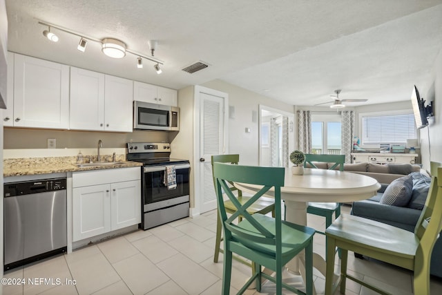 413 1st St S Unit 303, Jacksonville Beach, FL 32250 - kitchen with stainless steel appliances, white cabinetry, sink, light stone counters, and a textured ceiling