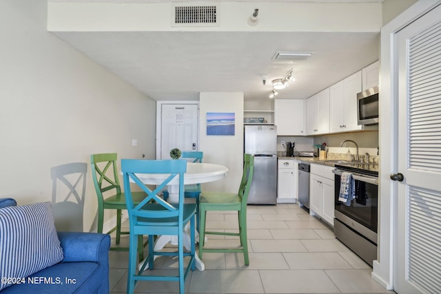 413 1st St S Unit 303, Jacksonville Beach, FL 32250 - kitchen featuring white cabinetry, sink, light tile patterned flooring, and stainless steel appliances