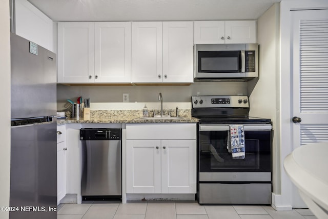 413 1st St S Unit 303, Jacksonville Beach, FL 32250 - kitchen with stainless steel appliances, white cabinets, sink, and light stone counters