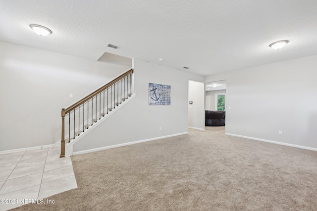 spare room featuring a textured ceiling and light colored carpet