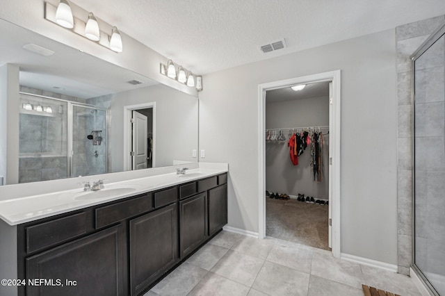 bathroom with tile patterned flooring, vanity, a textured ceiling, and a shower with shower door