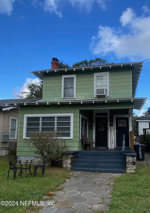 view of front property featuring a porch, cooling unit, and a front lawn