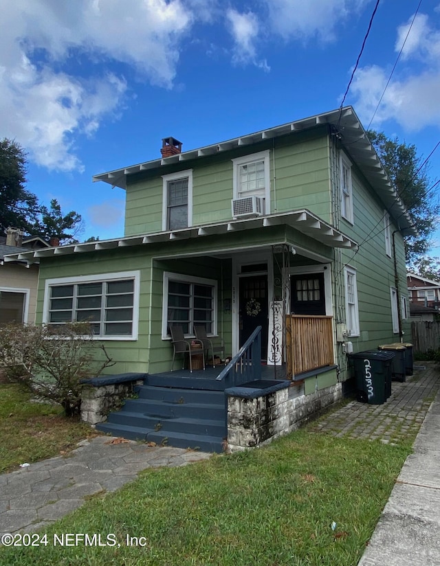 view of front of home featuring cooling unit, covered porch, and a front yard