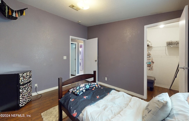 bedroom with dark hardwood / wood-style flooring, a closet, and a walk in closet