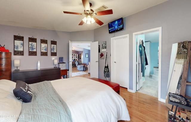 bedroom featuring light hardwood / wood-style flooring, ceiling fan, and ensuite bath