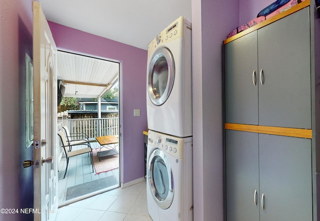 laundry area with light tile patterned flooring and stacked washer / dryer