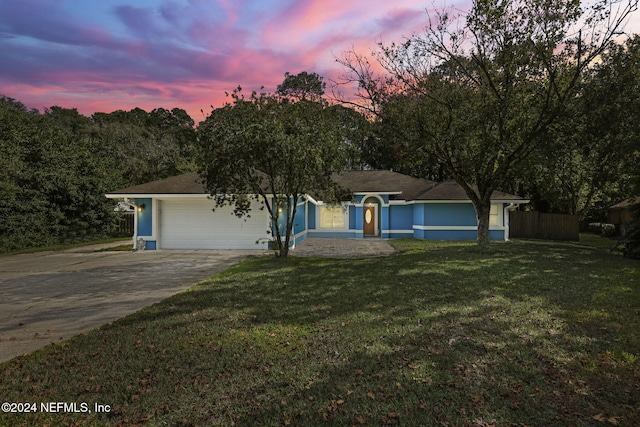 ranch-style house featuring a garage and a yard