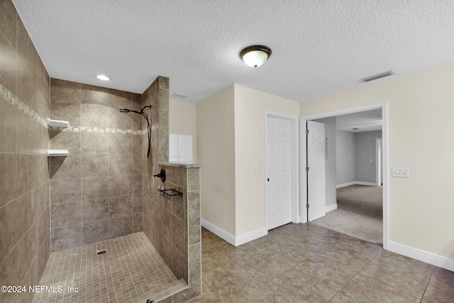 bathroom with tile patterned flooring, a textured ceiling, and tiled shower