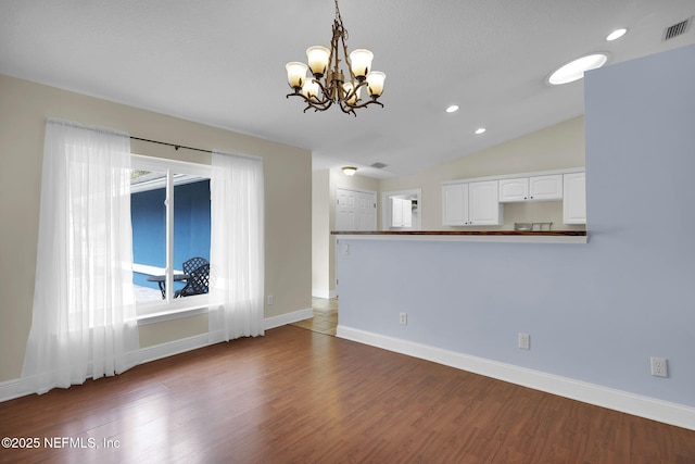 unfurnished living room with dark hardwood / wood-style floors, a chandelier, and vaulted ceiling