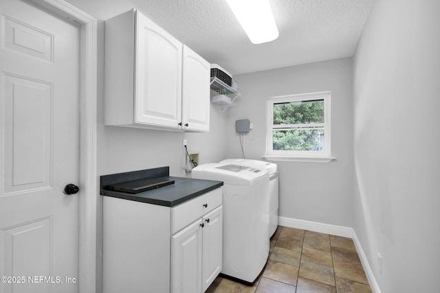 laundry room featuring separate washer and dryer, cabinets, and a textured ceiling