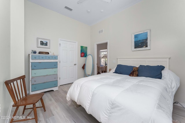 bedroom with ceiling fan, light hardwood / wood-style floors, and a high ceiling