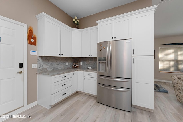 408 Third St, Saint Augustine, FL 32084 - kitchen with stainless steel fridge with ice dispenser, light wood-type flooring, white cabinets, and light stone counters